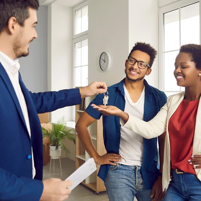 Real estate agent handing house keys to a happy couple in their new home