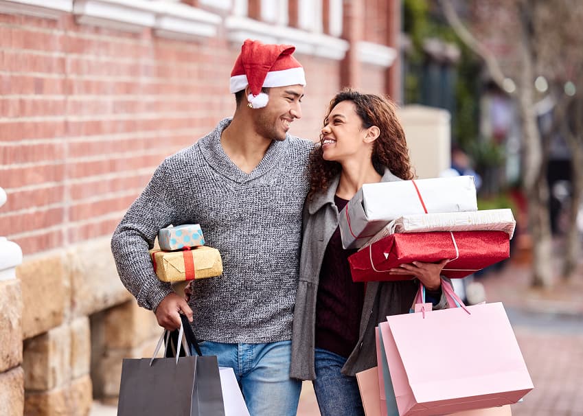 Couple carrying wrapped gifts and shopping bags during holiday shopping