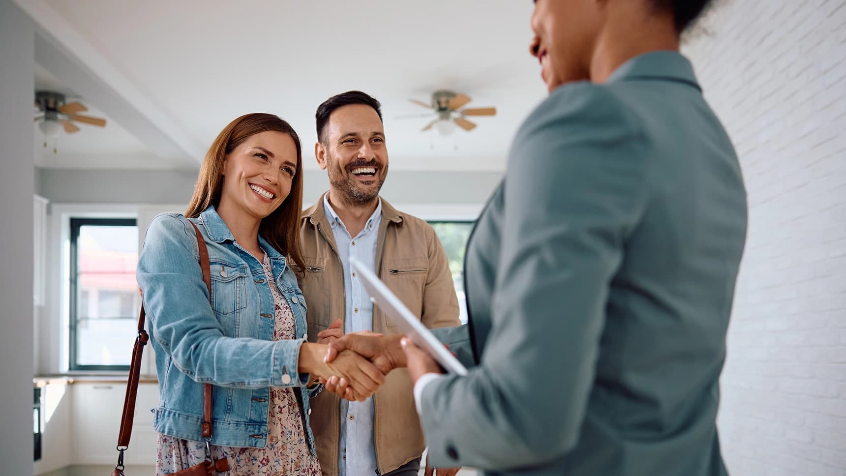 Couple shaking hands with a real estate agent after securing a home loan
