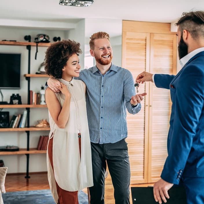 Real estate agent handing house keys to a happy couple in their new home