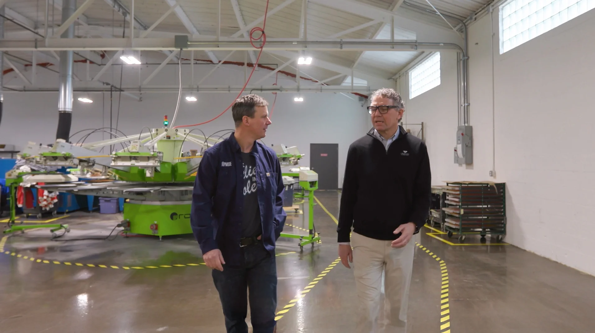Two men walking through a manufacturing facility discussing business loans
