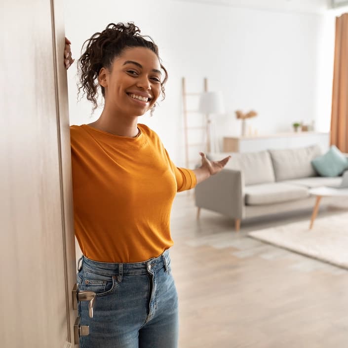 Happy woman opening the door to her new home purchased with an FHA loan