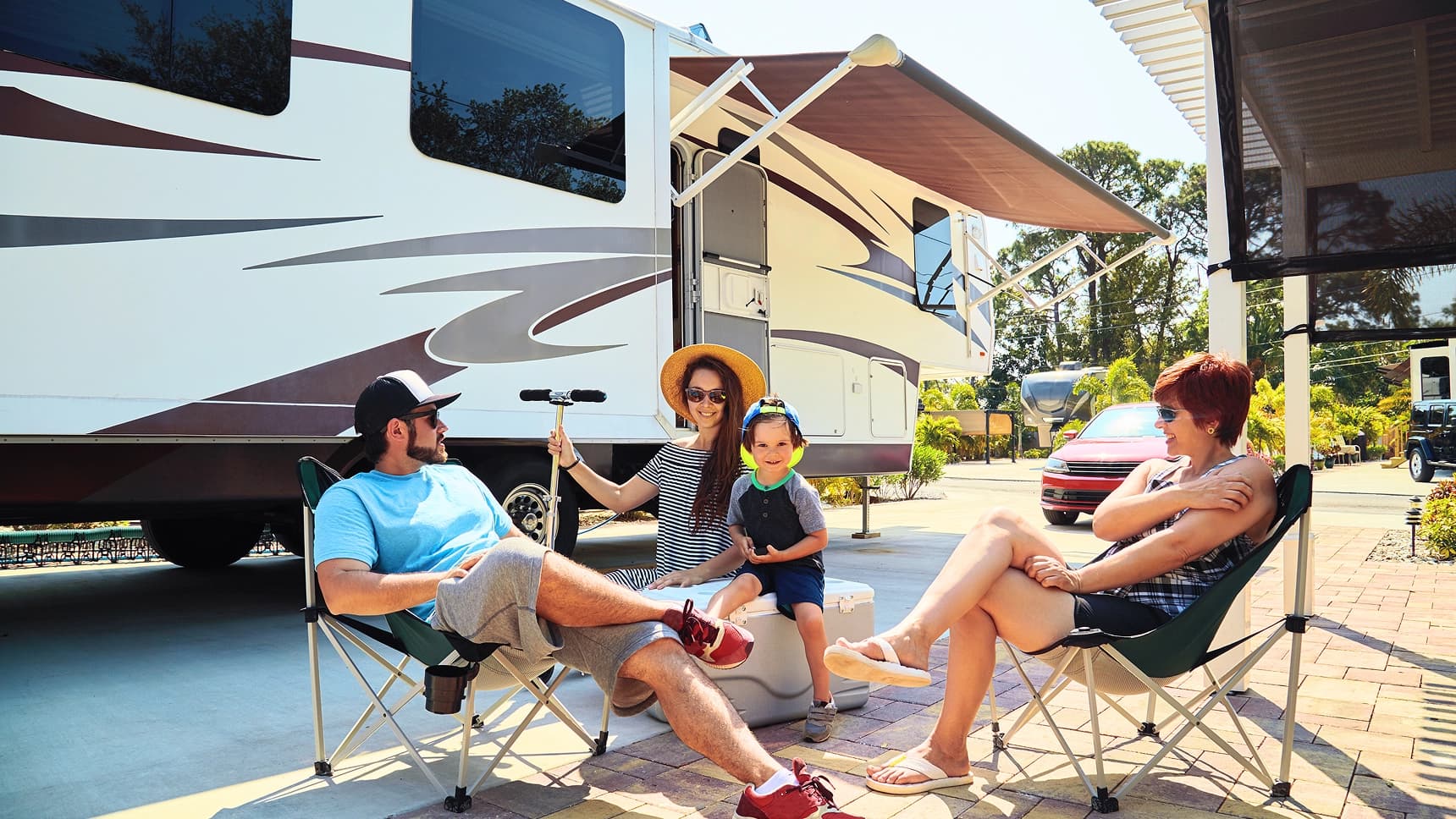 Family enjoying time together outdoors beside their RV at a sunny campsite