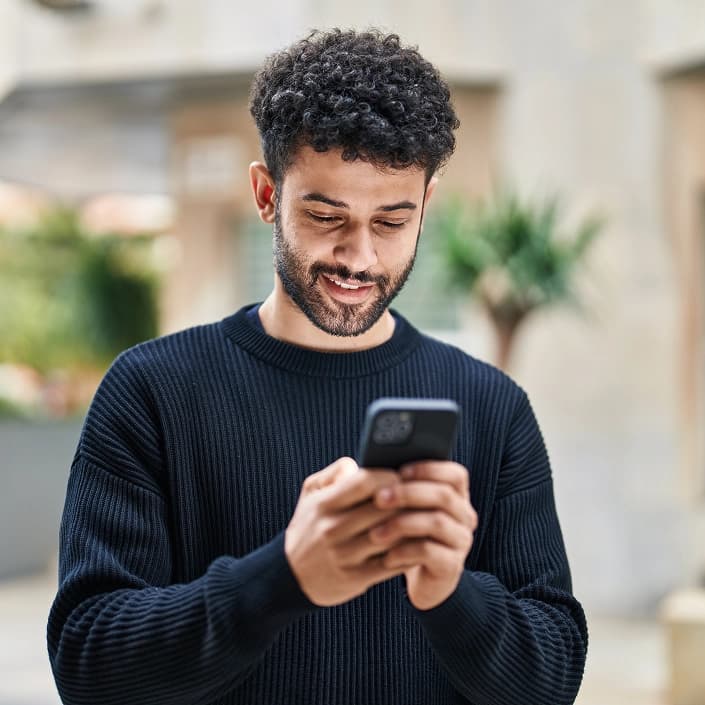 Smiling man using a mobile banking app on his smartphone outdoors