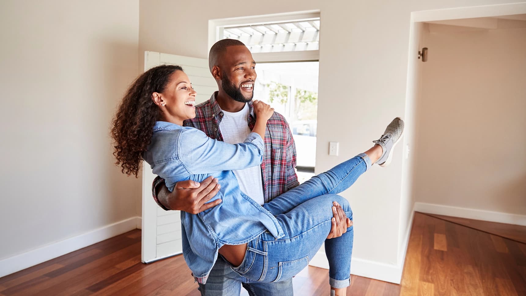 Joyful couple celebrating in an empty home after closing on a mortgage loan