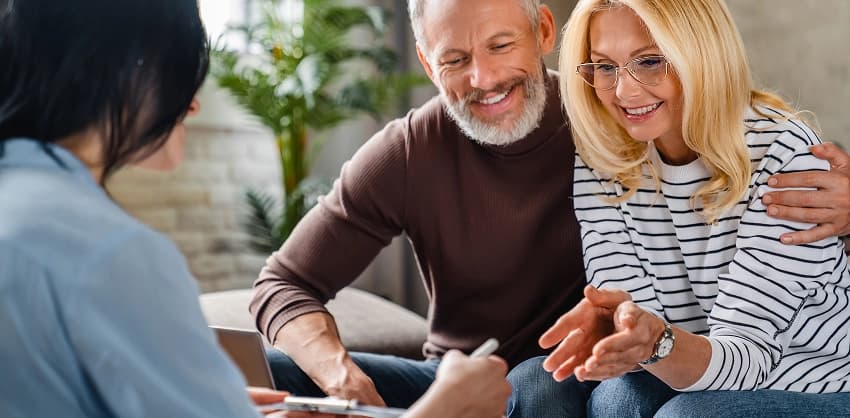 A smiling couple reviewing documents with a financial advisor during a planning consultation