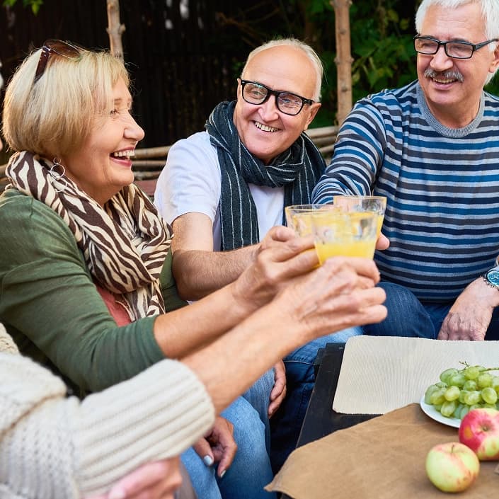 Group of friends laughing and toasting drinks outdoors at a casual gathering