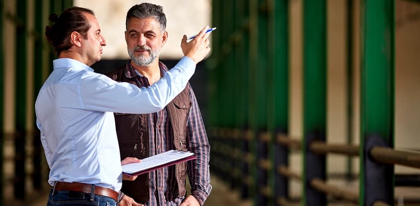 Two men outdoors reviewing a clipboard and discussing a home improvement loan or property inspection