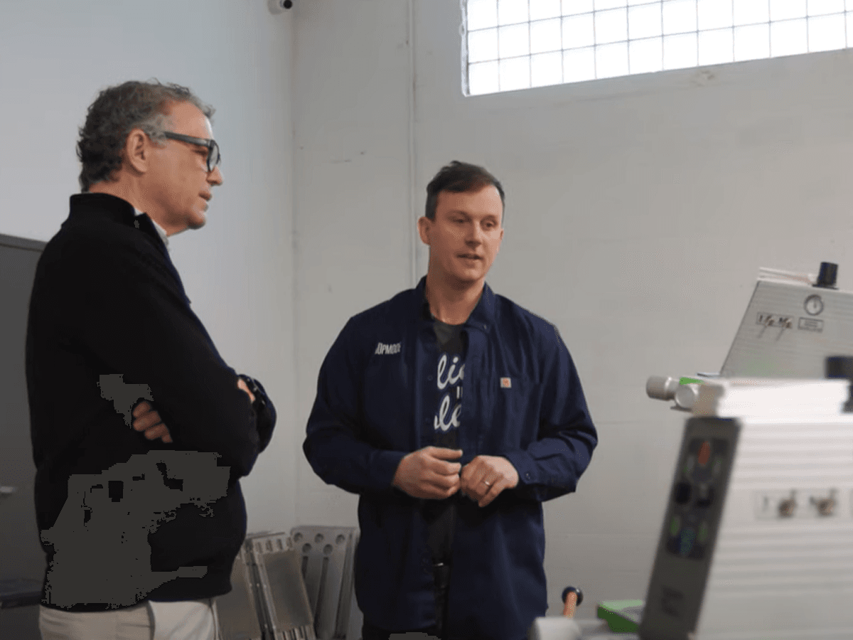 Two men having a conversation near industrial equipment in a workshop