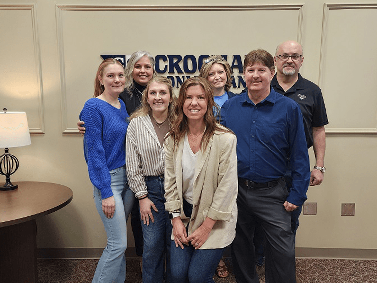 Croghan Bank team members smiling together in front of the bank's lobby sign