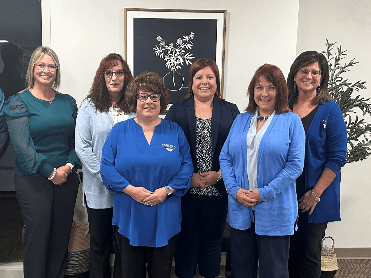 Croghan Bank wealth management and financial planning team members smiling together in a modern office setting