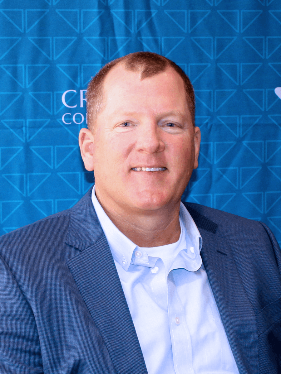Smiling Croghan Bank professional in a blue blazer and light blue shirt posed in front of a blue branded backdrop