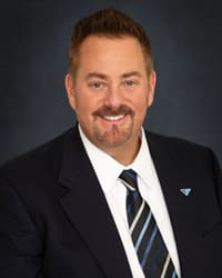 Professional man with a beard wearing a dark suit and striped tie with a Croghan Bank pin