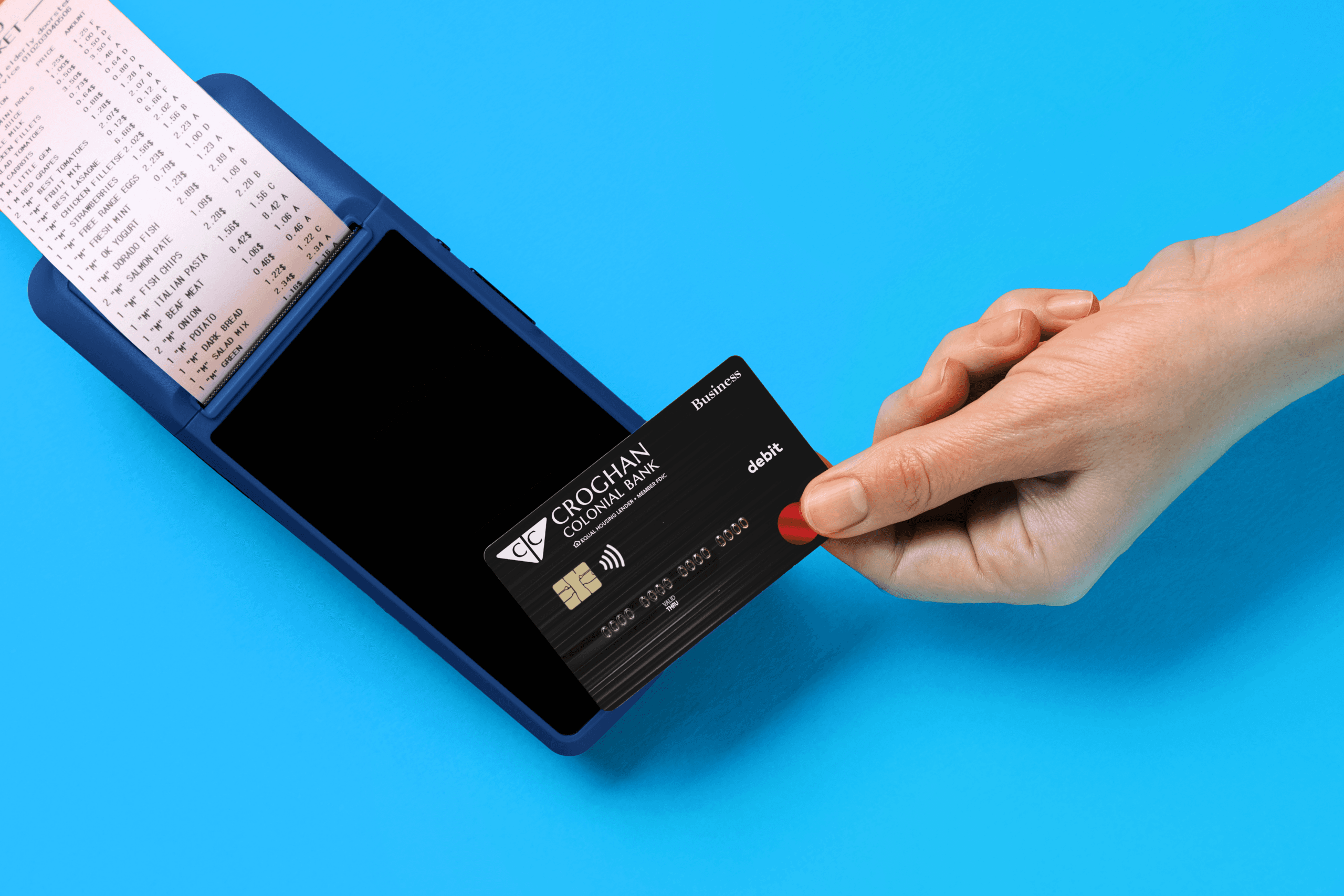 Hand inserting a Croghan Colonial Bank business debit card into a payment terminal with a printed receipt.